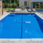 Rectangular swimming pool with paved surround and loungers, swimming pool price guide