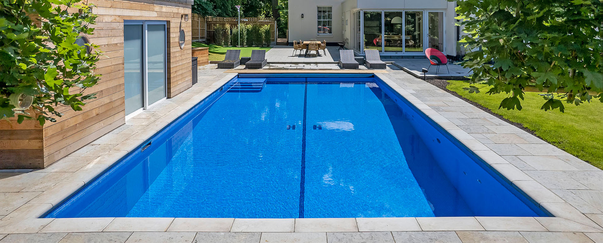 Rectangular swimming pool with paved surround and loungers, swimming pool price guide