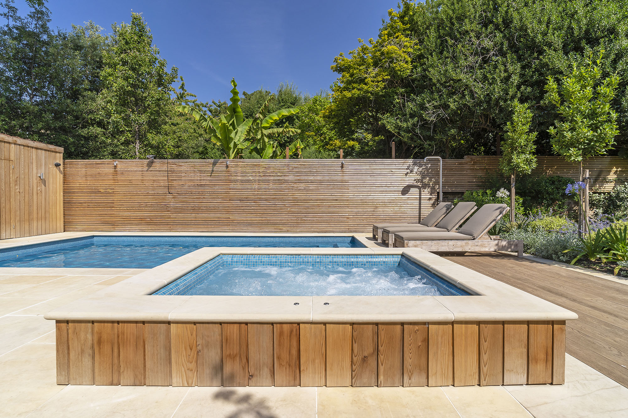 Swimming pool and spa with timber deck and sandstone coping, fibreglass pool prices guide