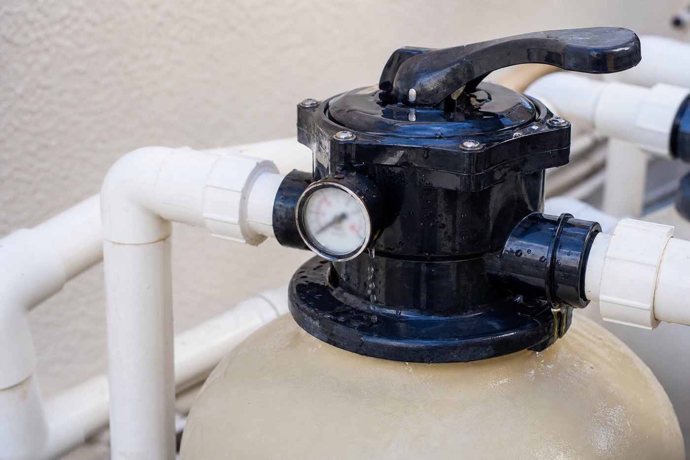 Swimming pool multiport valve and filter pressure gauge on a sand filter with white PVC pipework